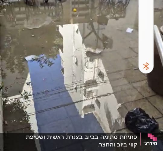 שלולית גדולה על המדרכה עם השתקפות בניין